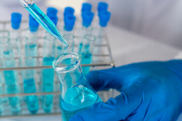 Biochemistry laboratory research, Scientist or medical in lab coat holding test tube with using reagent with drop of color liquid over glass equipment working at the laboratory.