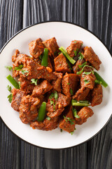Tibs is a popular Ethiopian dish of sautéed beef flavored with niter kibbeh and berbere closeup in the plate on the table. Vertical top view from above