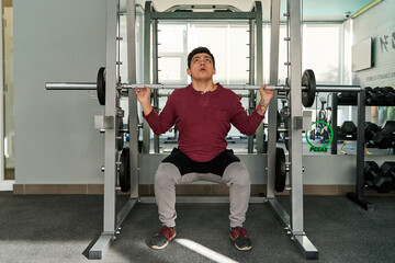 young latin man performing squats on the smith machine