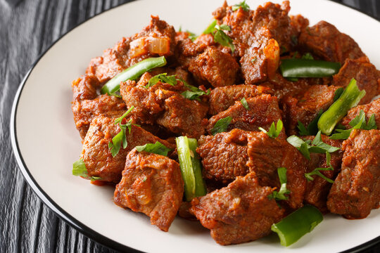 Ethiopian cuisine Tibs fried beef meat in a spicy vegetable sauce close-up in a plate on the table. Horizontal