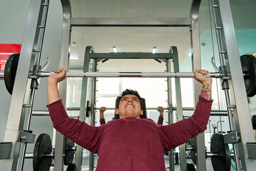 young latino male performing an incline bench press at the gym