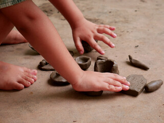 Kids making soil made toy on concrete surface without face image.