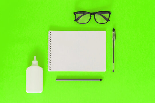 Office supplies. The concept of education. Everything for school and office. Pens, pencils, notepad, glasses, and everything for studying. Black and white on a bright green background. Flatly. Mock up
