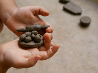 Soil made toys presented on kids hand on cemented field.