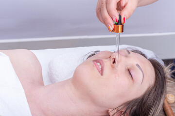 Applying essential oil with a pipette on the girl's face to massage the face and neck. Anti-aging face massage