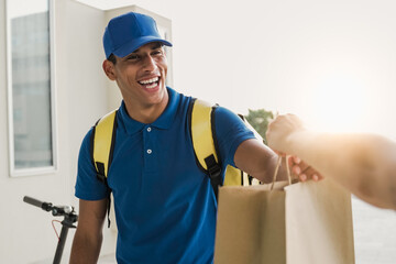 Hispanic delivery man delivering fast food meal package in paper bag from cafeteria restaurant - Deliver customer service - Focus on face