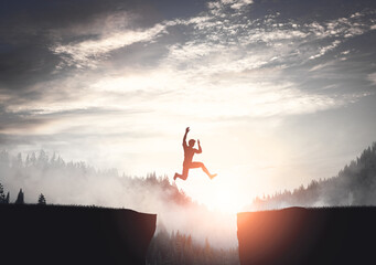 Fototapeta Man jumping between cliffs at sunset. obraz
