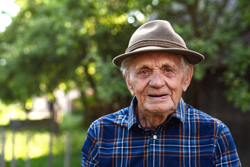 Naklejka na ściany i meble Portrait of elderly man standing outdoors in garden, looking at camera.