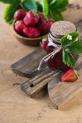 Strawberry jam in a jar on a wooden board. Fermented berries.