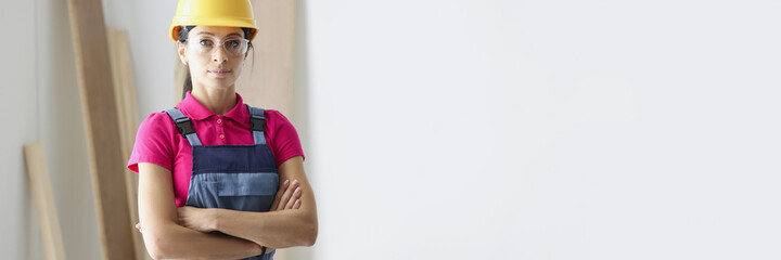 Woman builder in protective helmet standing in workshop