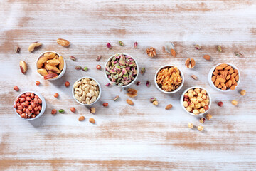 Nuts variety, overhead flat lay shot of many bowls of different nuts with a place for text, on a rustic wooden background