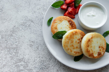 Cottage cheese pancakes, ricotta fritters on ceramic plate with  fresh strawberry.