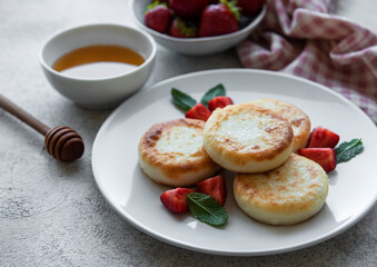 Cottage cheese pancakes, ricotta fritters on ceramic plate with  fresh strawberry.