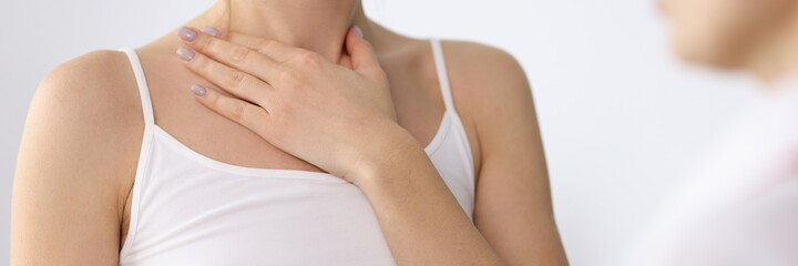 Woman hand showing sore neck at doctor appointment closeup