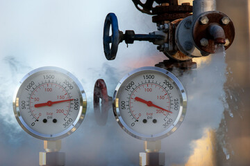 water pressure gauge meters against a leaky pipeline which comes out hot steam and hot water under...