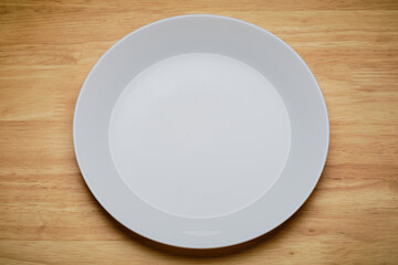 top view over head shot of white empty cuisine tableware dish isolated on wooden dinner table in...