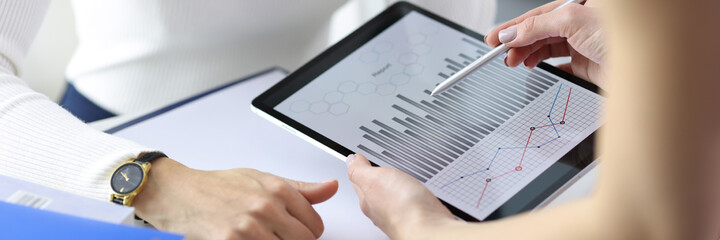 Businesswoman showing colleague graph on digital tablet closeup
