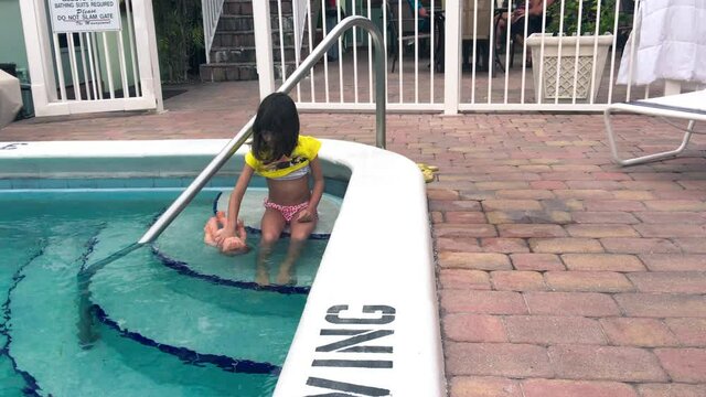 Young girl playing with her doll along the hotel pool