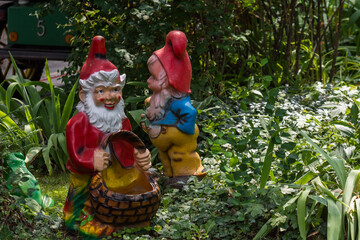 two dwarfs between plants in a mini golf course from a amusement park - obrazy, fototapety, plakaty