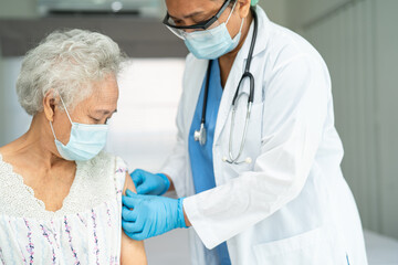 Elderly Asian senior woman wearing face mask getting covid-19 or coronavirus vaccine by doctor make...