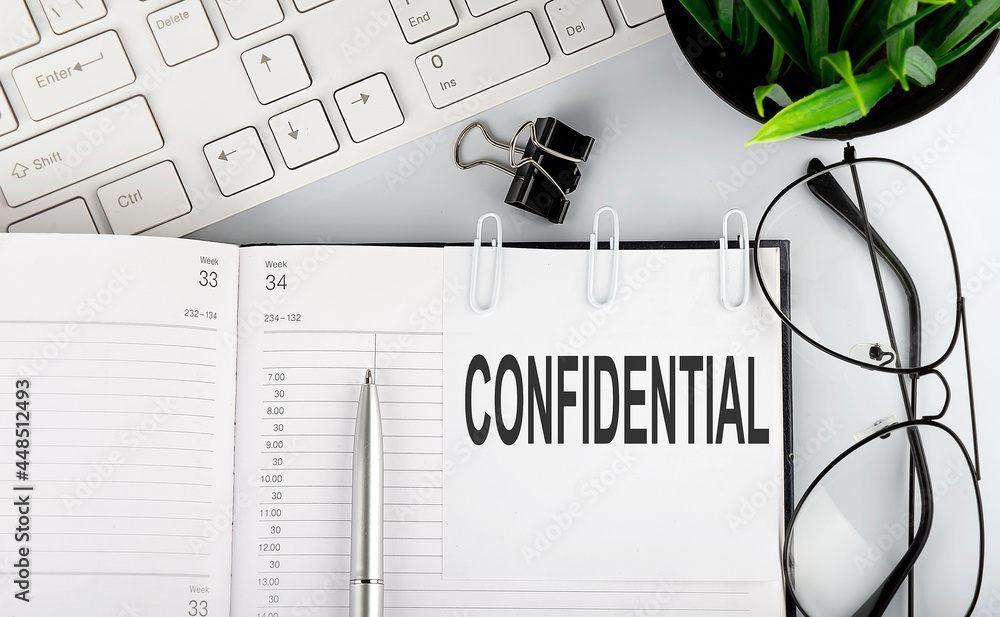 Poster text confidential stickers on the notebook with keyboard and glasses.