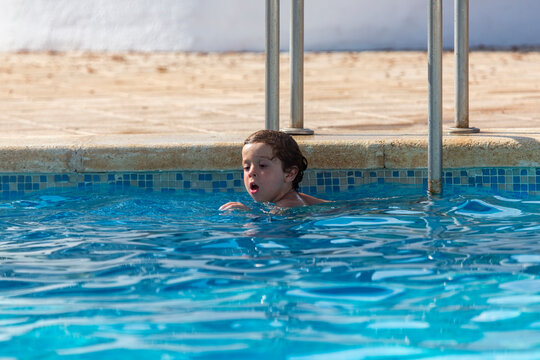 child in the water in the pool near the ladder