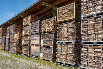 Brennholz in gestapelten alten Gitterboxen unter einem industriellen Dach im Freien