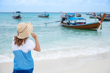 Fototapeta na wymiar Asian woman tourist holding hat walking on the beach at Lipe island, Satun, Thailand. Enjoy summer vacation travel.
