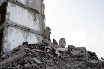 A pile of construction debris made of gray concrete fragments against the gray sky and the remains...