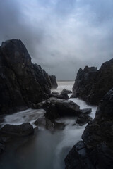 Beautiful Long exposure Image of the ocean waves hitting the big sharp rocks at the beach side of Arambol beach, Goa.