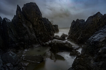 Beautiful Long exposure Image of the ocean waves hitting the big sharp rocks at the beach side of Arambol beach, Goa.