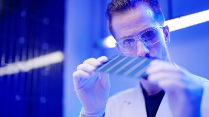 Male technician wearing gloves and glasses check solar cell quality control