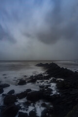 Beautiful Long exposure Image of the ocean waves hitting the big sharp rocks at the beach side of Arambol beach, Goa.