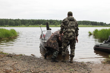 Fisher mans lin camouflage clothing launches the equipped alloy fishing boat away from the river...