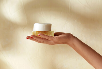 natural cosmetics, hygiene and beauty concept - hand holding bar of craft soap on beige background