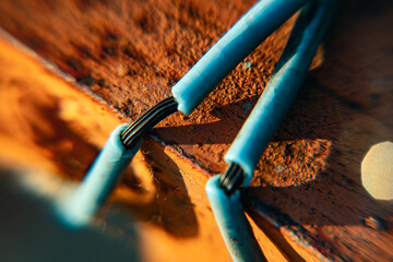 two electrical cables with damaged insulation on a metal rusty surface, fragment, macro, blurred background