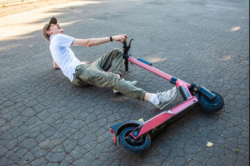 A young man got into an accident on an electronic scooter, lies on the asphalt and screams in pain © Kathleen