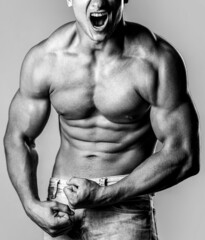 Muscular male strains muscles and screams. Muscular bodybuilder posing over white background. Black...