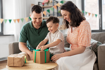 family, holidays and people concept - happy mother, father and little son opening birthday presents...