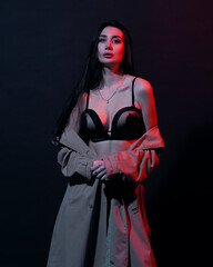 Woman in trench-coat and underwear in neon studio