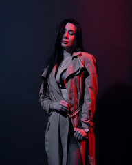 Woman in trench-coat and underwear in neon studio