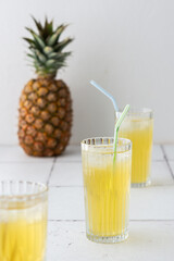 Delicious sweet refreshing pineapple juice with ice in glasses with a straw