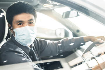 Fototapeta na wymiar Young saleman wear surgical mask Asian man driving car He smile and thumbs up so happy drive To travel during outbreak coronavirus covid-19 to male smile image smiling