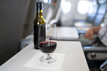 A glass with red wine and a small bottle in the background on the table of a passenger in an...