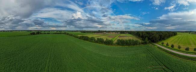 Aerial panorama view shot with drone of a rainbow over stormy sky. Rural landscape with rainbow over dark stormy sky in a countryside at summer day. High quality photo