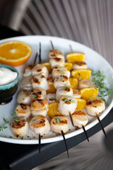 Grilled scallops on wooden skewers with orange and fresh thyme.
