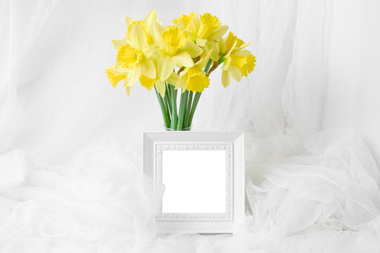 mockup of spring postcard, invitation, banner. bouquet of beautiful yellow daffodils and white photo frame with place for text. minimalistic holiday concept - mothers day, easter