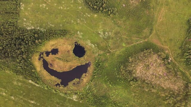 A sly smile of the lake, like a face, from a bird's eye view, beauty in nature. Pond as a smiley and emoji. A smile on a natural lake, a view from the top, as if in a fairy tale. UHD 4K.