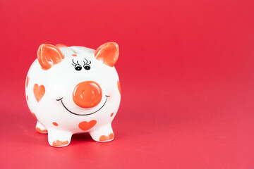 Cute piggy bank with red hearts and red background, copy space