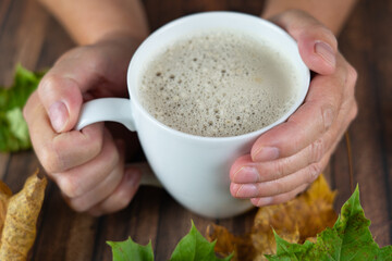 Woman holds a cup of hot cappuccino in hand